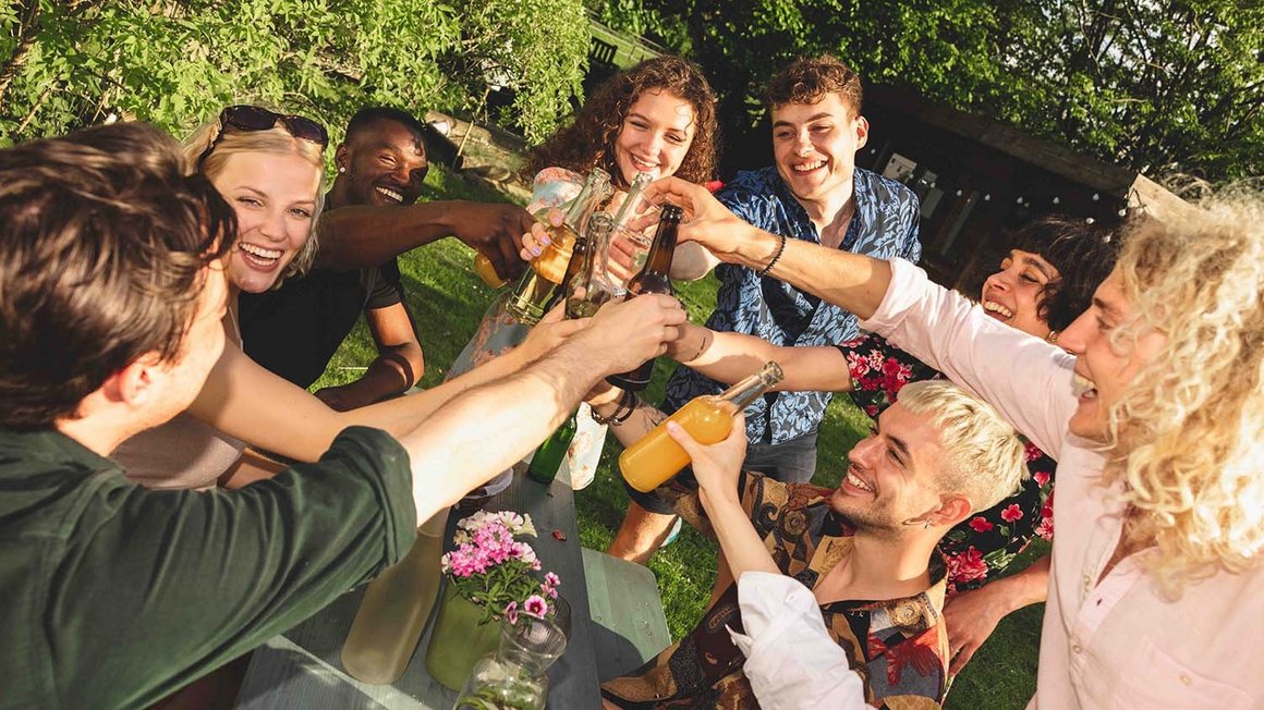 Eine Gruppe junger Menschen stößt mit Gläsern an. 