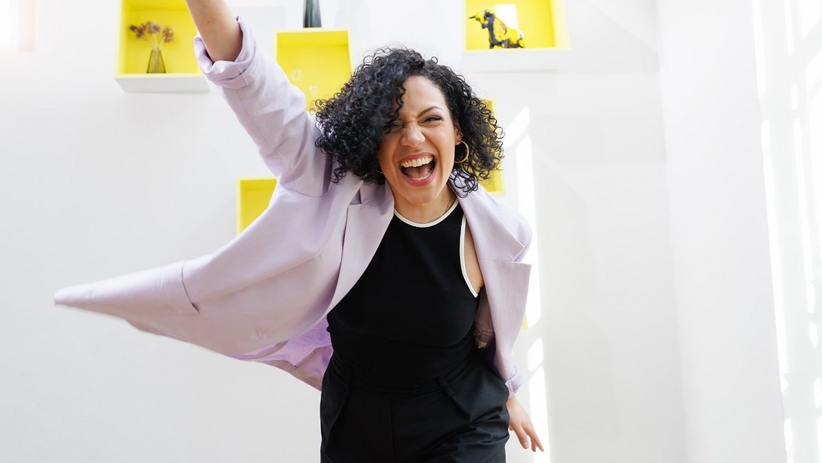 Teammotivation: 9 Tipps, wie Sie Ihr Team motivieren Frau hebt lachend den Arm in die Luft