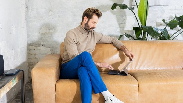 Mann arbeitet mit Tablet auf der Couch – Work-Life-Integration    Mann arbeitet mit Tablet auf der Couch – Work-Life-Integration