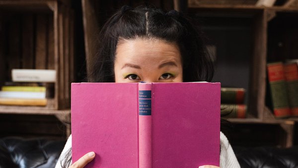 Junge Frau hält ein Buch vors Gesicht