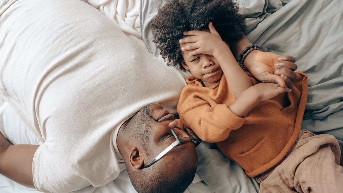 Vater und Sohn liegen nebeneinander auf dem Bett