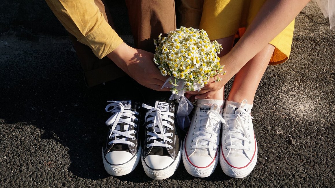 Paar auf dem Boden sitzend mit Blumen in der Hand – Hochzeitsplanung