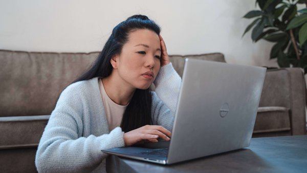 Warum Schulden gefährlich werden können Eine Frau sitzt an ihrem Laptop