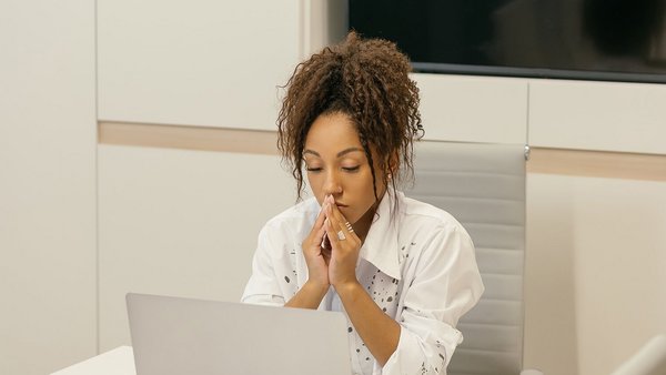 Junge Frau sitzt grübelnd vor Laptop – Resilienz Junge Frau sitzt grübelnd vor Laptop – Resilienz