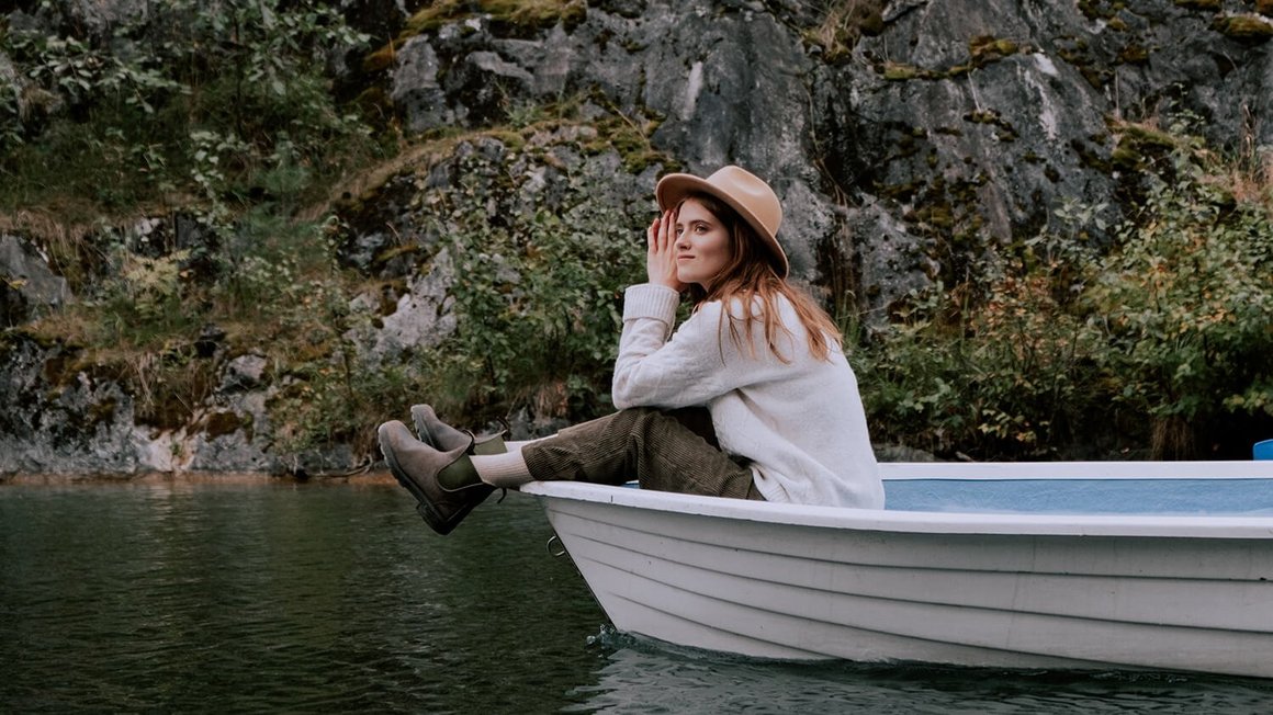 Frau sitzt in einem Boot – Im Ausland reisen