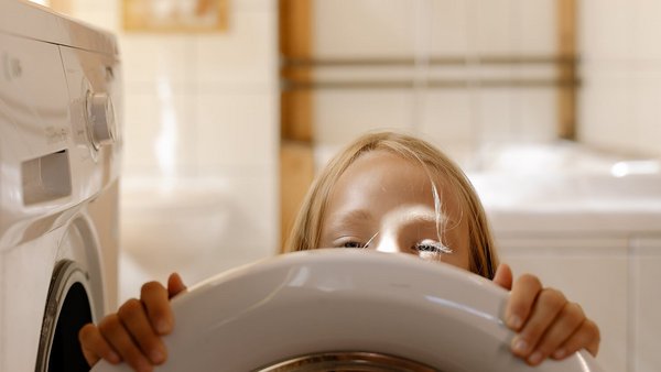 Mädchen vor einer Waschmaschine - Energiekosten senken