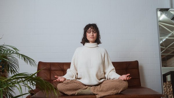 Gute Gewohnheiten: Wie Sie produktive Routinen richtig nutzen und umsetzen Frau sitzt entspannt auf der Couch und nutzt gute Routinen