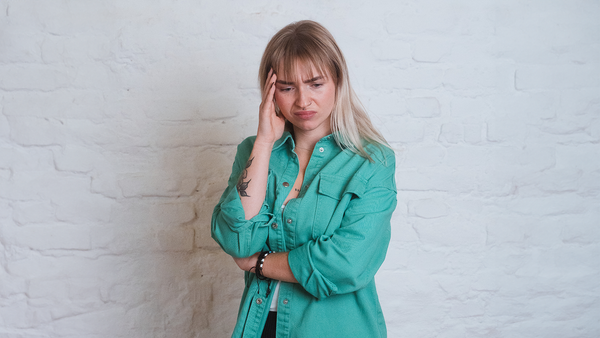 Krank zur Arbeit: Präsentismus durch eine resiliente Unternehmenskultur vermeiden Frau hält sich die Hand an den Kopf