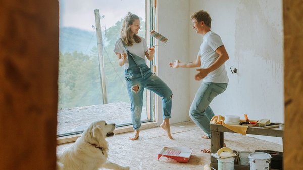 Pärchen tanzt mit Hund zusammen im neuen Haus – Baufinanzierung