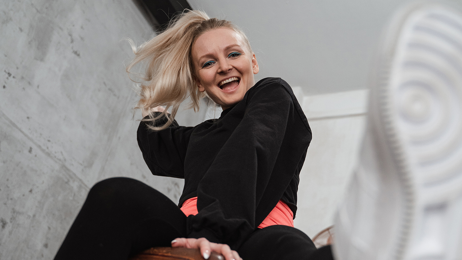 Frau macht Turnübung und lacht – Fit am Arbeitsplatz