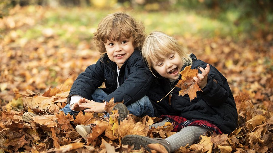 Zwei Kinder sitzen im Herbstlaub