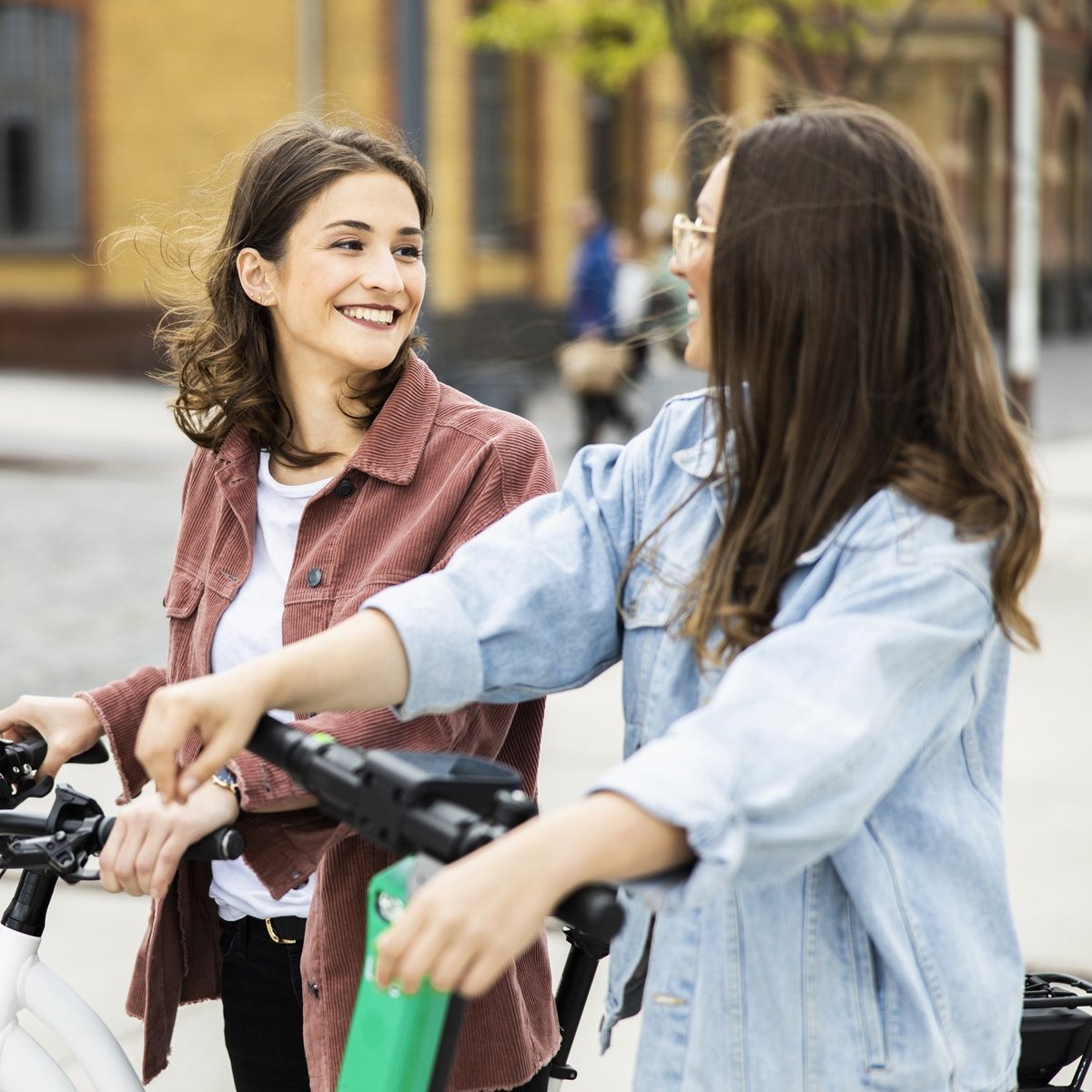 Zwei Frauen auf Fahrrad und E-Scooter unterhalten sich