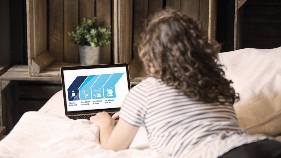 Frau liegt im Bett und informiert sich am Laptop über Finanzlösungen